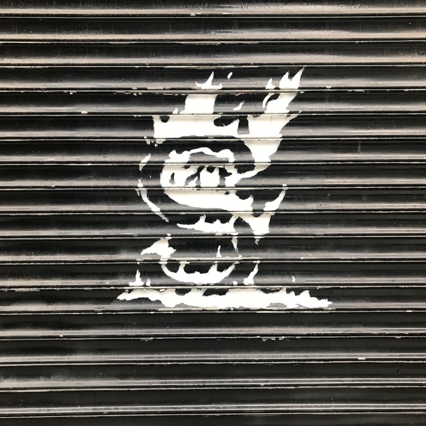 Photograph of bodega shutters, painted black with flaming S logo